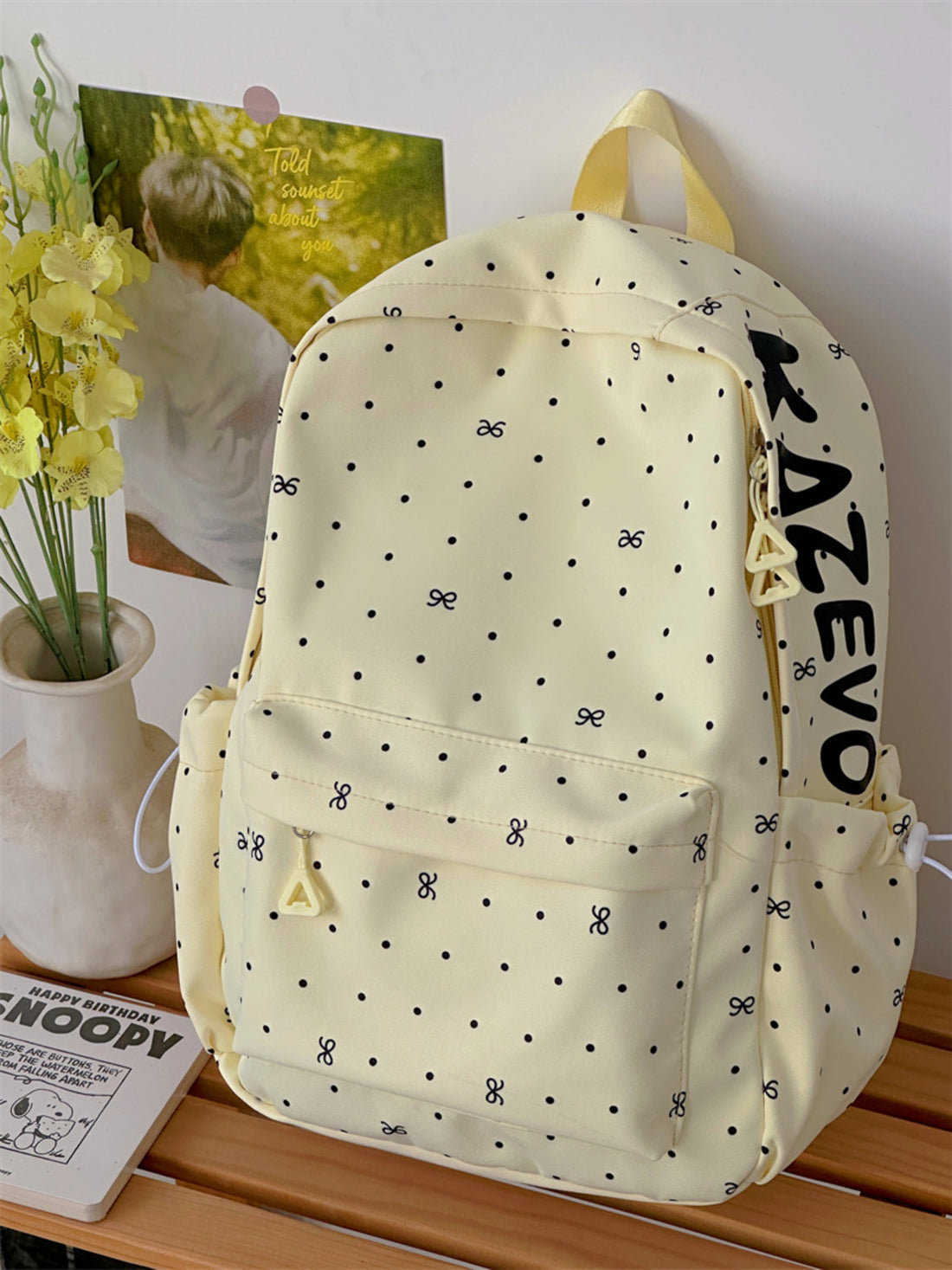 Yellow polka dot backpack with bow pattern and large side zipper detail.