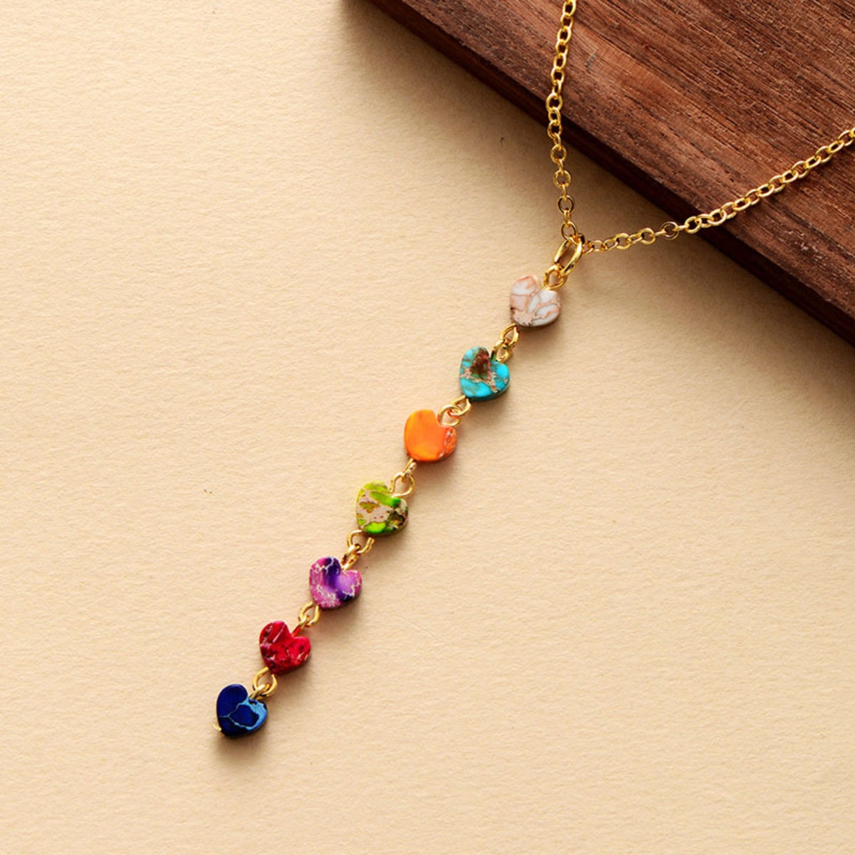 Rainbow heart cascade necklace with multicolor stone charms on a gold chain.