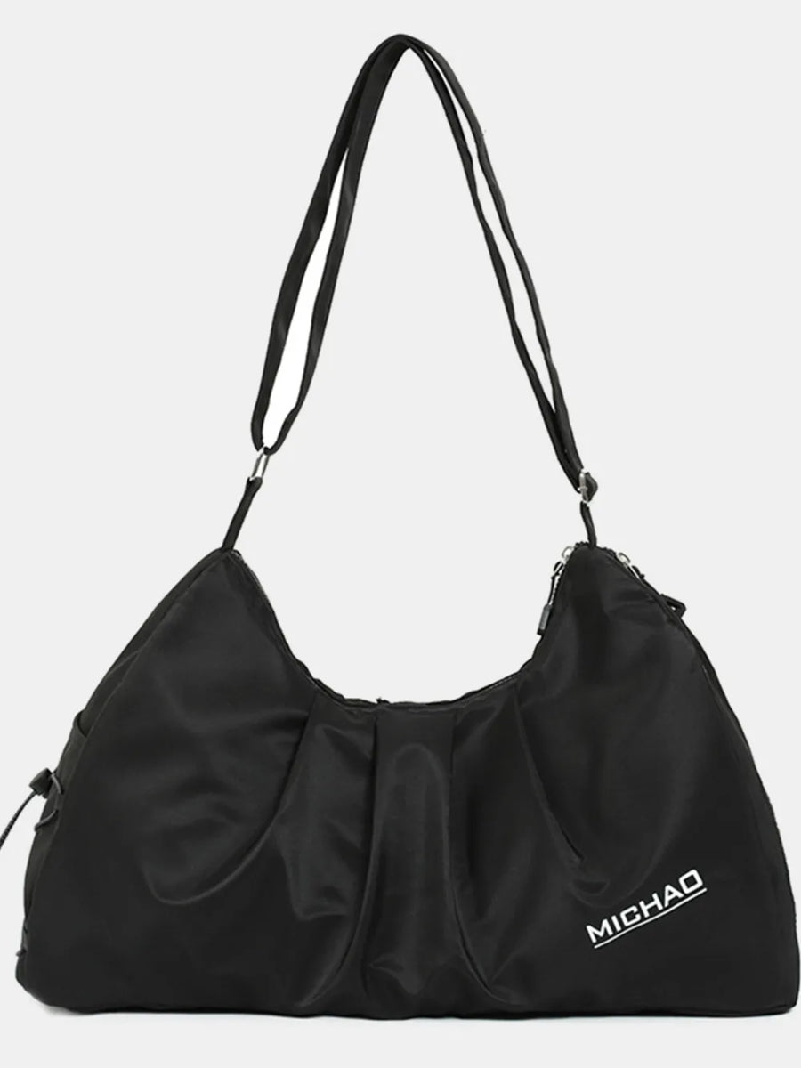 Black gathered pleat crossbody bag with adjustable strap and logo detail.