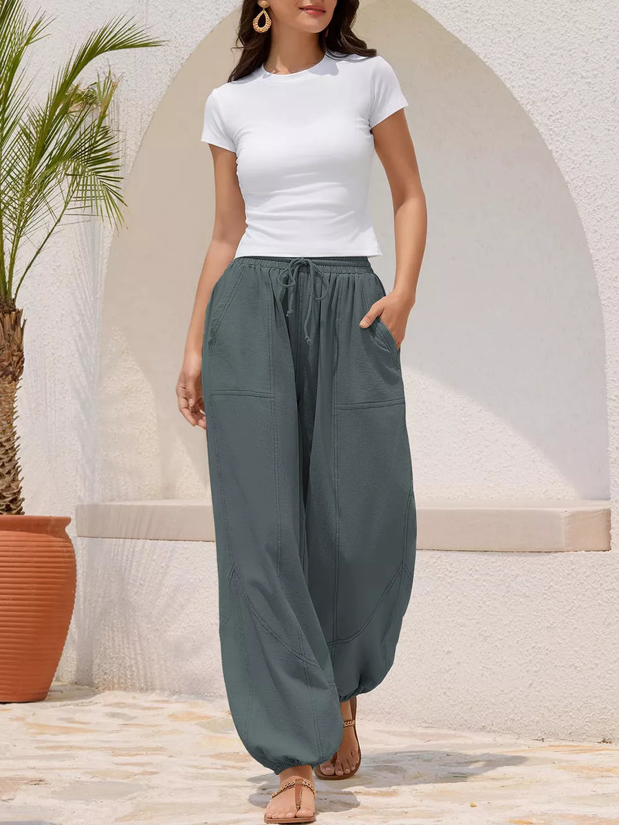 Grey relaxed harem pants with drawstring and contrast stitching detail.