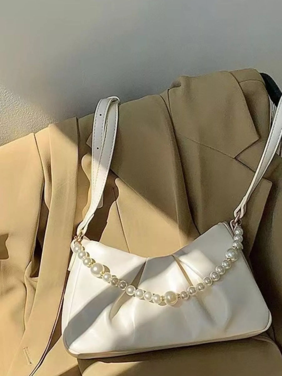 White ruched shoulder bag with pearl strap detail.