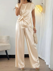 Champagne satin twist-front top with cap sleeves and flowing wide-leg pants.