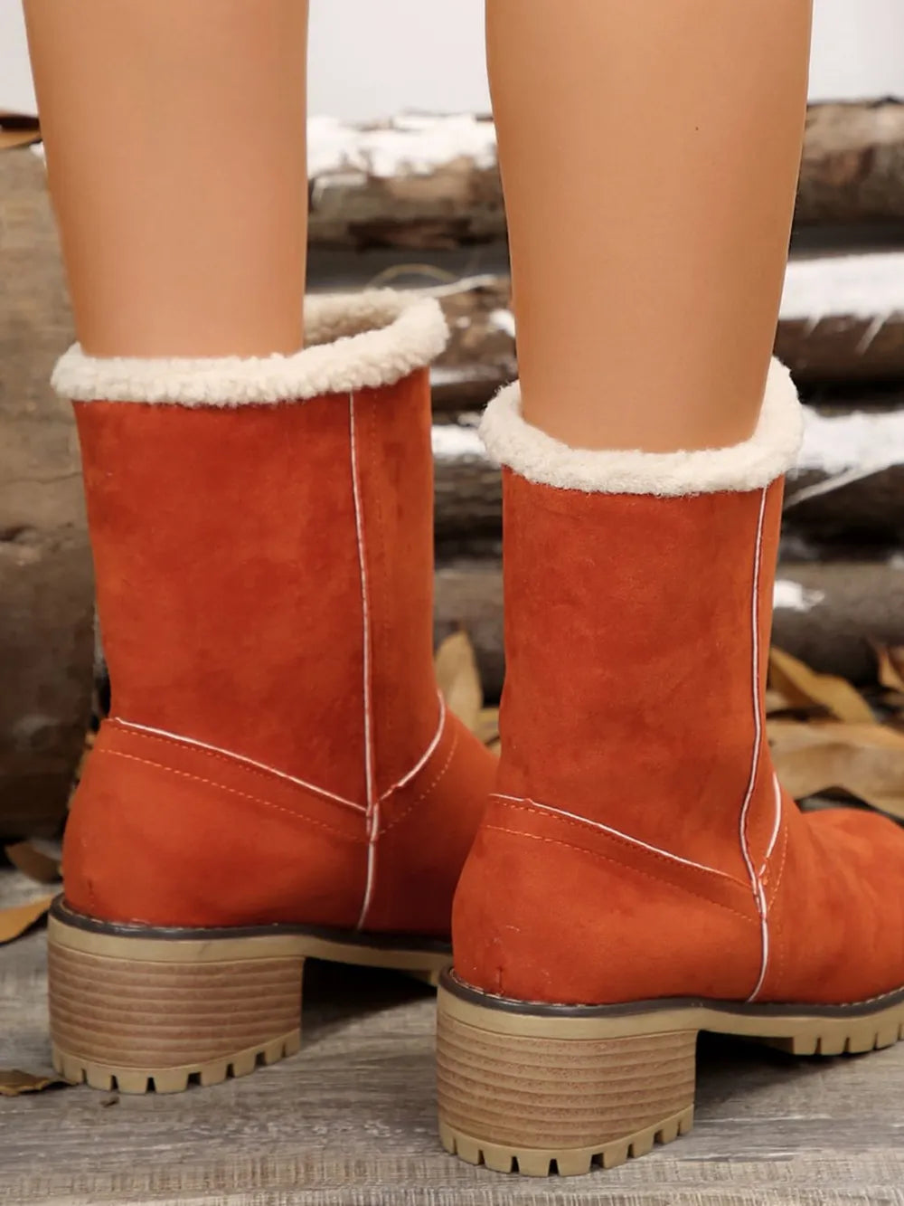 Orange suede ankle boots with sherpa trim and contrast stitching on a lug sole.