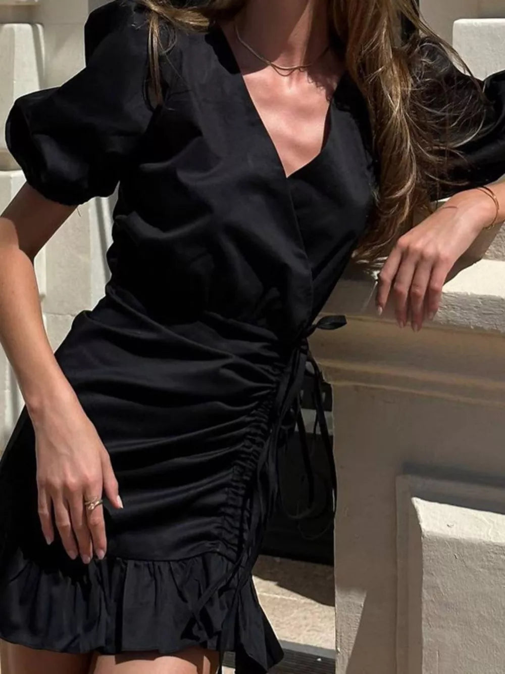 Black mini dress with V-neck, puff sleeves, ruched side, and ruffled hem