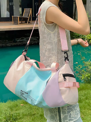 Vibrant pastel nylon duffle bag with color-blocked panels and text detail, adjustable pink strap.