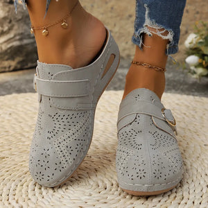 Gray laser-cut buckle mule wedges with perforated floral pattern and adjustable strap.