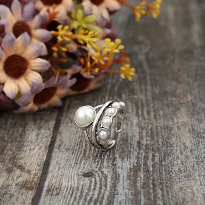 Silver ring with a large pearl and a cluster of smaller pearls on a textured band.
