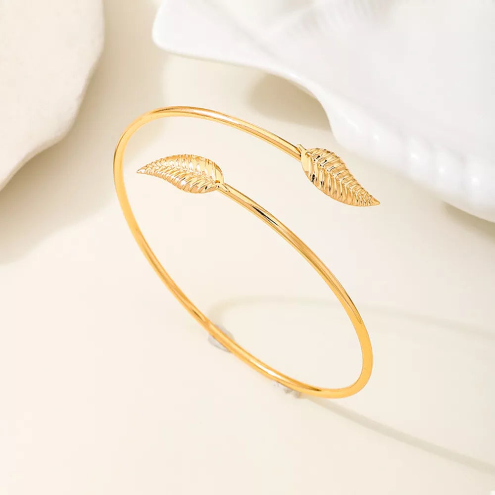 Gold bracelet featuring open cuff and leaf