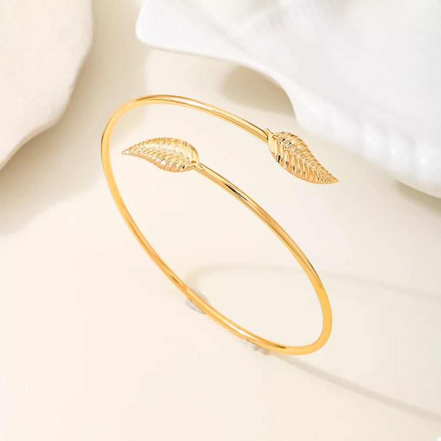 Gold bracelet featuring open cuff and leaf