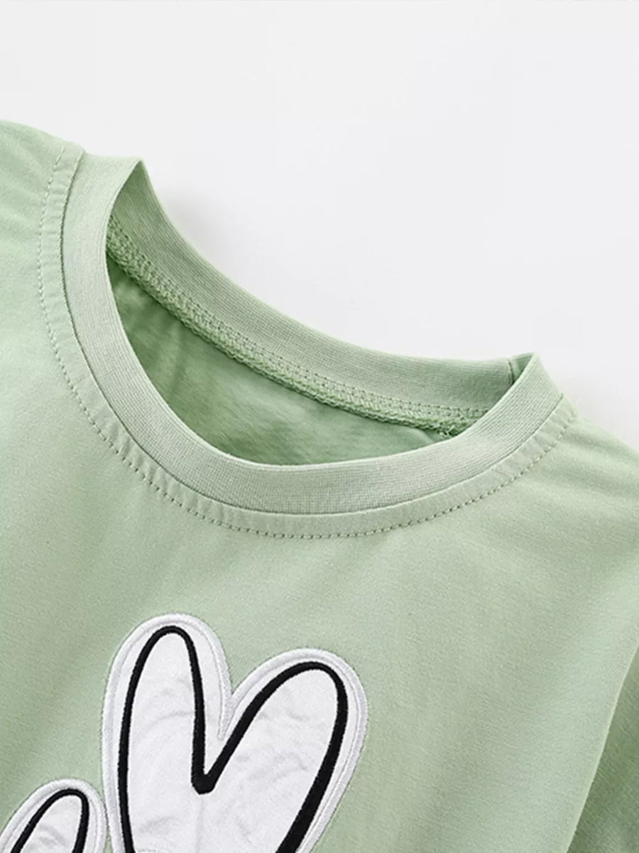 Light green cotton blend crew neck tee with a white heart graphic and ruffle sleeves.