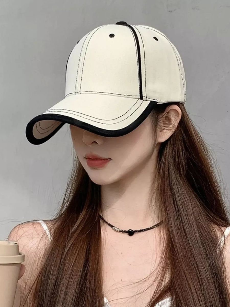 Cream white cotton baseball cap with contrast stitching and black trim.