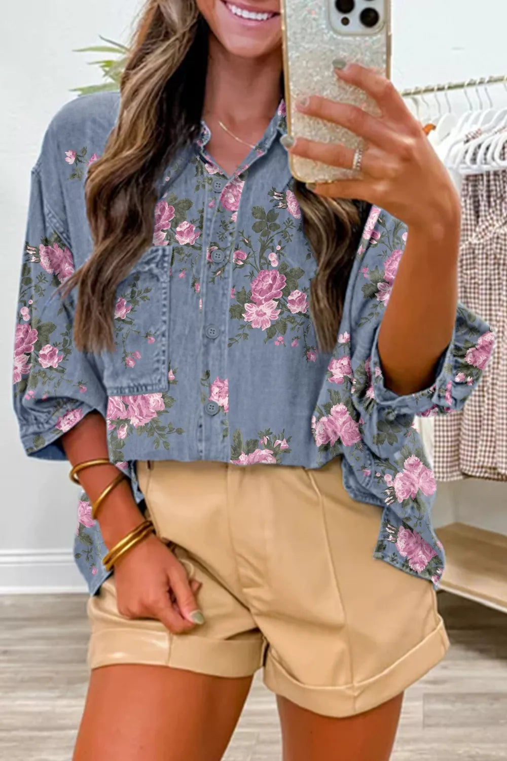 Denim button-up shirt with pink floral print, collared, long sleeves, and chest pockets.