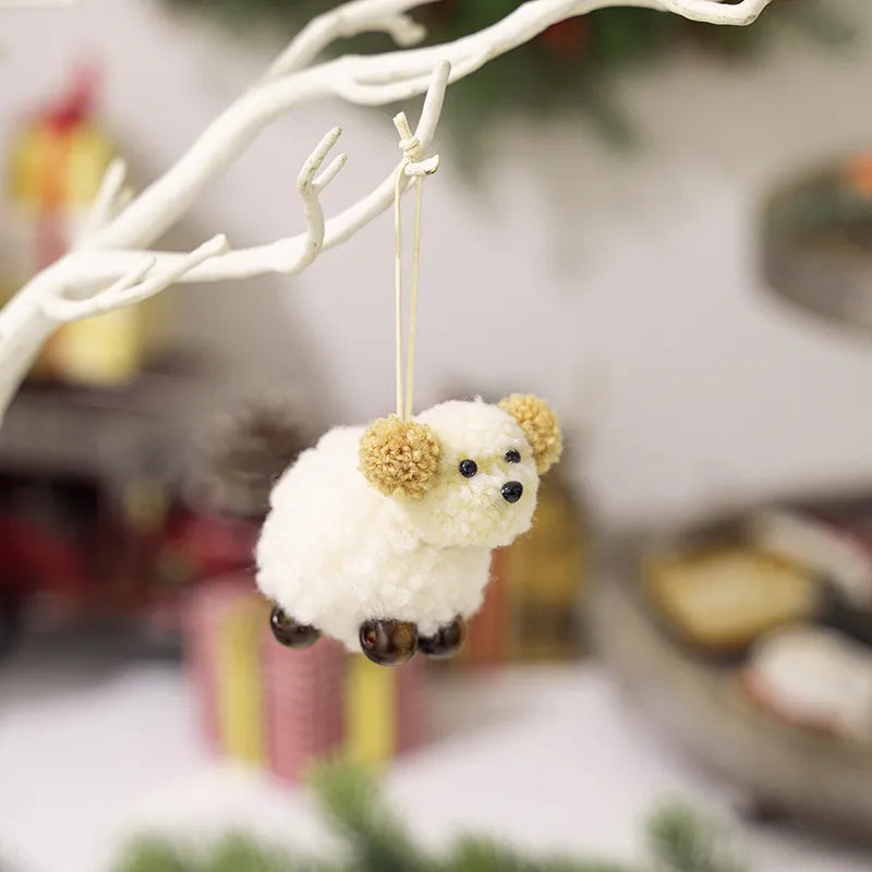 Woolly sheep ornament with pom-pom ears, black eyes, and brown feet, hanging from a branch.