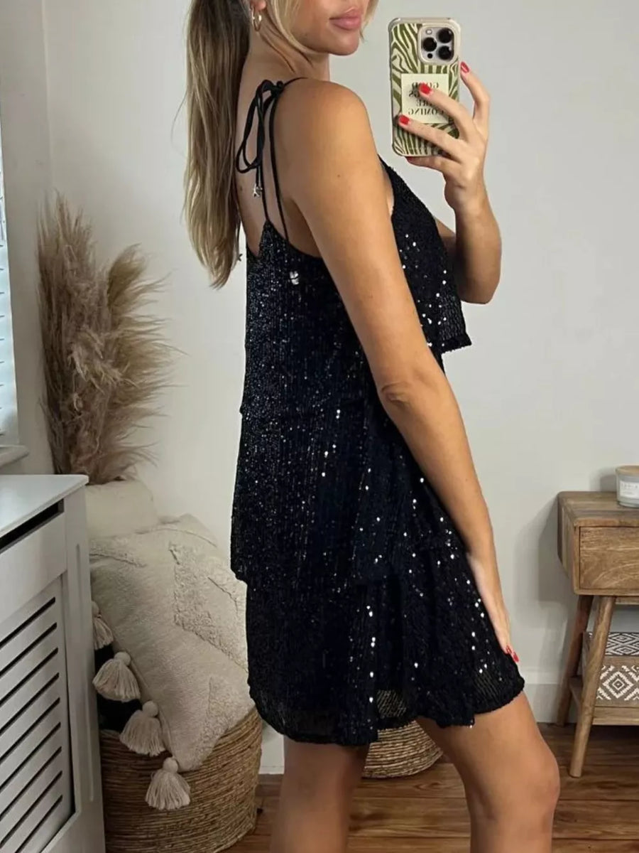Black sequin mini dress with tie shoulders and tiered skirt.