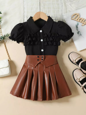Black puff sleeve top with ruffles and white buttons, paired with a brown faux leather pleated skirt.