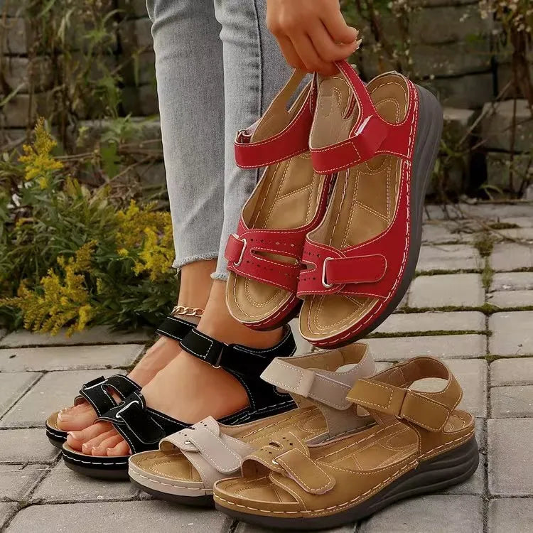 Red perforated velcro wedge sandals with adjustable straps, shown with black, beige, and brown sandals.