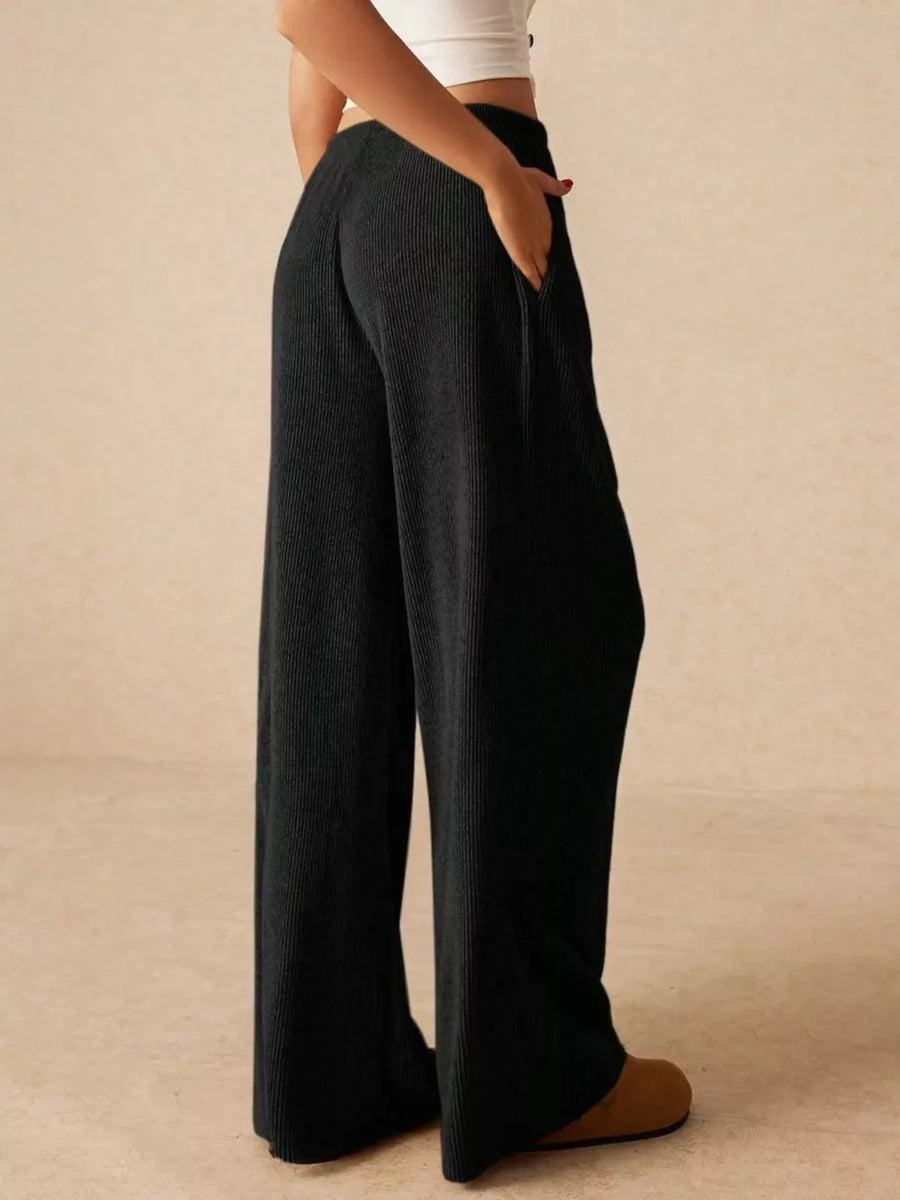 Black ribbed wide-leg drawstring pants with pockets, styled casually.
