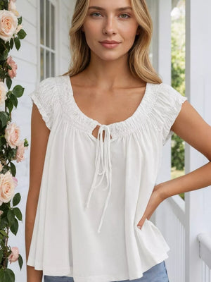 White tie-front gathered blouse with short sleeves and a scoop neckline.