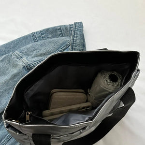Silver padded nylon tote bag with interior pockets holding wallet, phone, and umbrella.