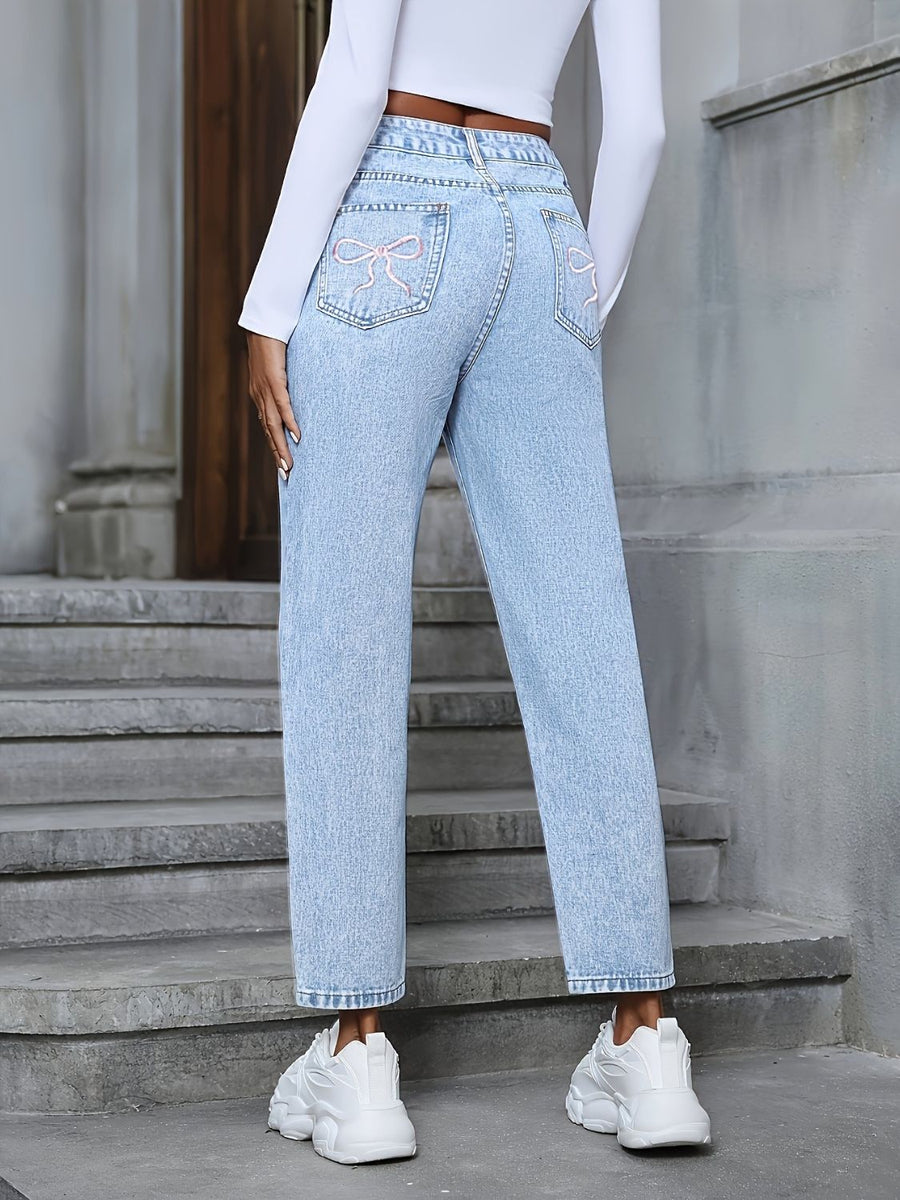 Light wash boyfriend jeans with distressed details and pink bow embroidery on back pockets.