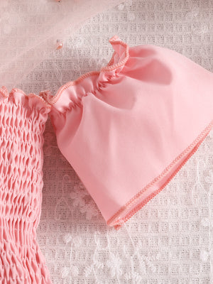 Pink smocked off-shoulder top with ruffled sleeves and tulle detail.