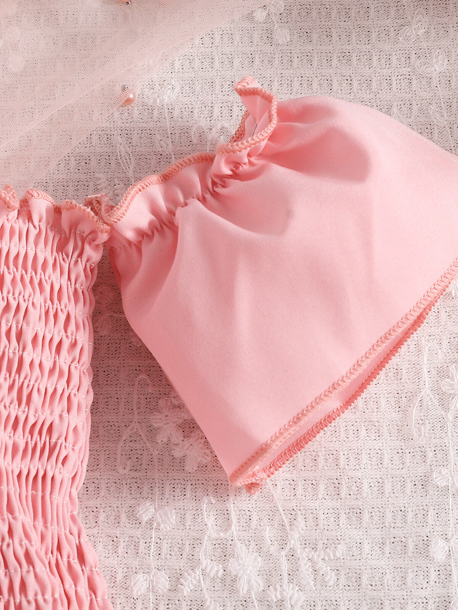 Pink smocked off-shoulder top with ruffled sleeves and tulle detail.
