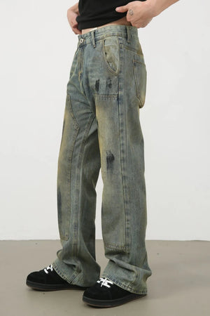 Distressed medium wash carpenter jeans with black paint splatters and a relaxed fit.