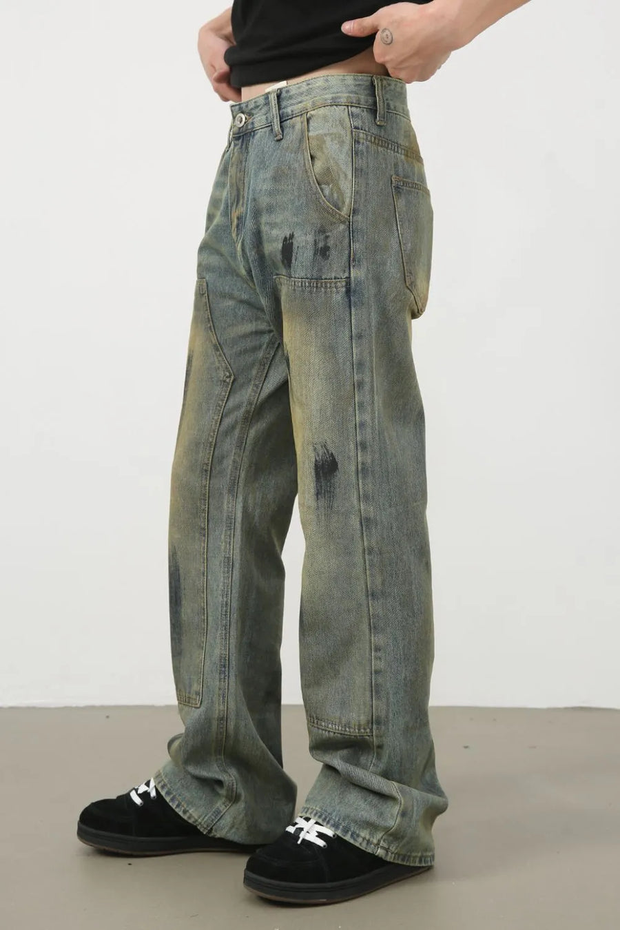 Distressed medium wash carpenter jeans with black paint splatters and a relaxed fit.