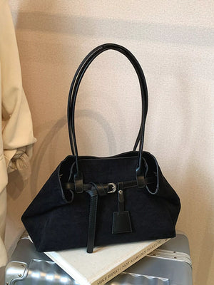 Black suede shoulder bag with buckle detail and leather straps.