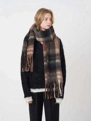 Textured plaid fringe scarf in brown and black, styled with a black sweater.