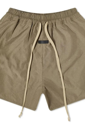 Taupe nylon drawstring shorts with curved hem and black logo tag.
