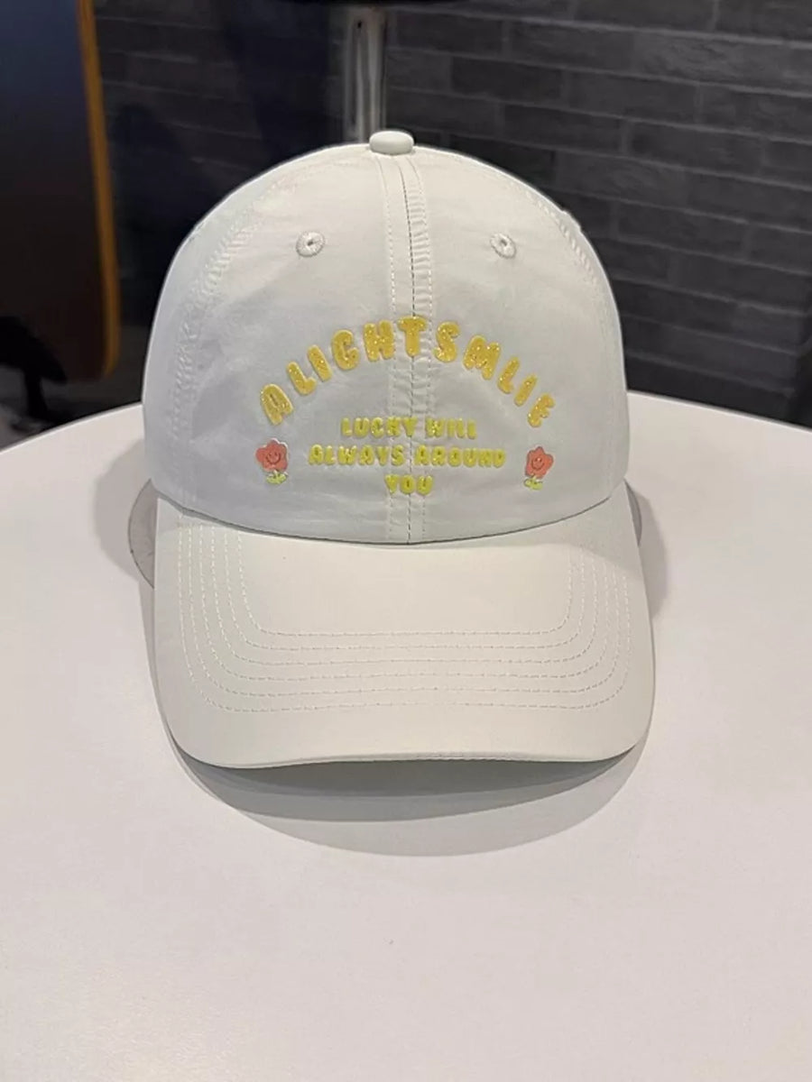 White baseball cap with yellow embroidered text and flower details.