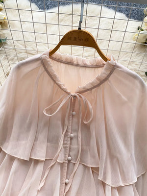 Pink chiffon blouse with ruffled neckline, tie detail, and button front.