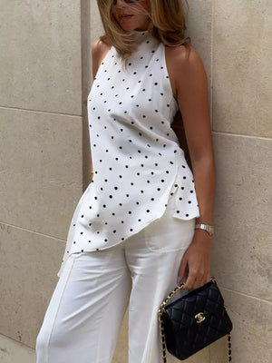 White polka dot halter top with asymmetrical hem, paired with white wide-leg pants.