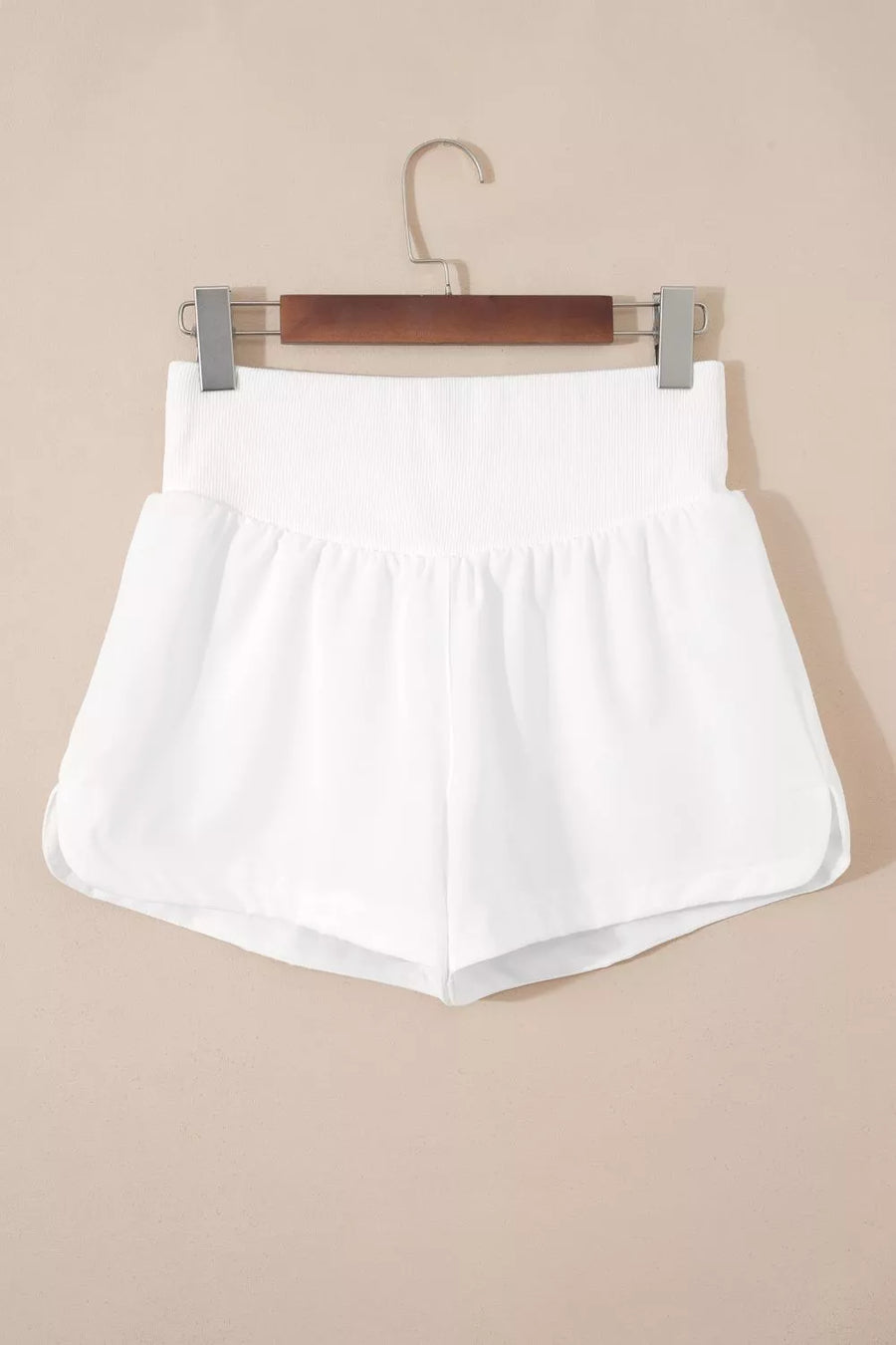White relaxed fit shorts with a ribbed high-rise waist and dolphin hem.