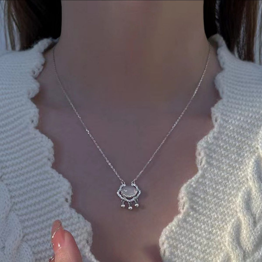Auspicious lock pendant necklace with chalcedony charm and dangling accents.