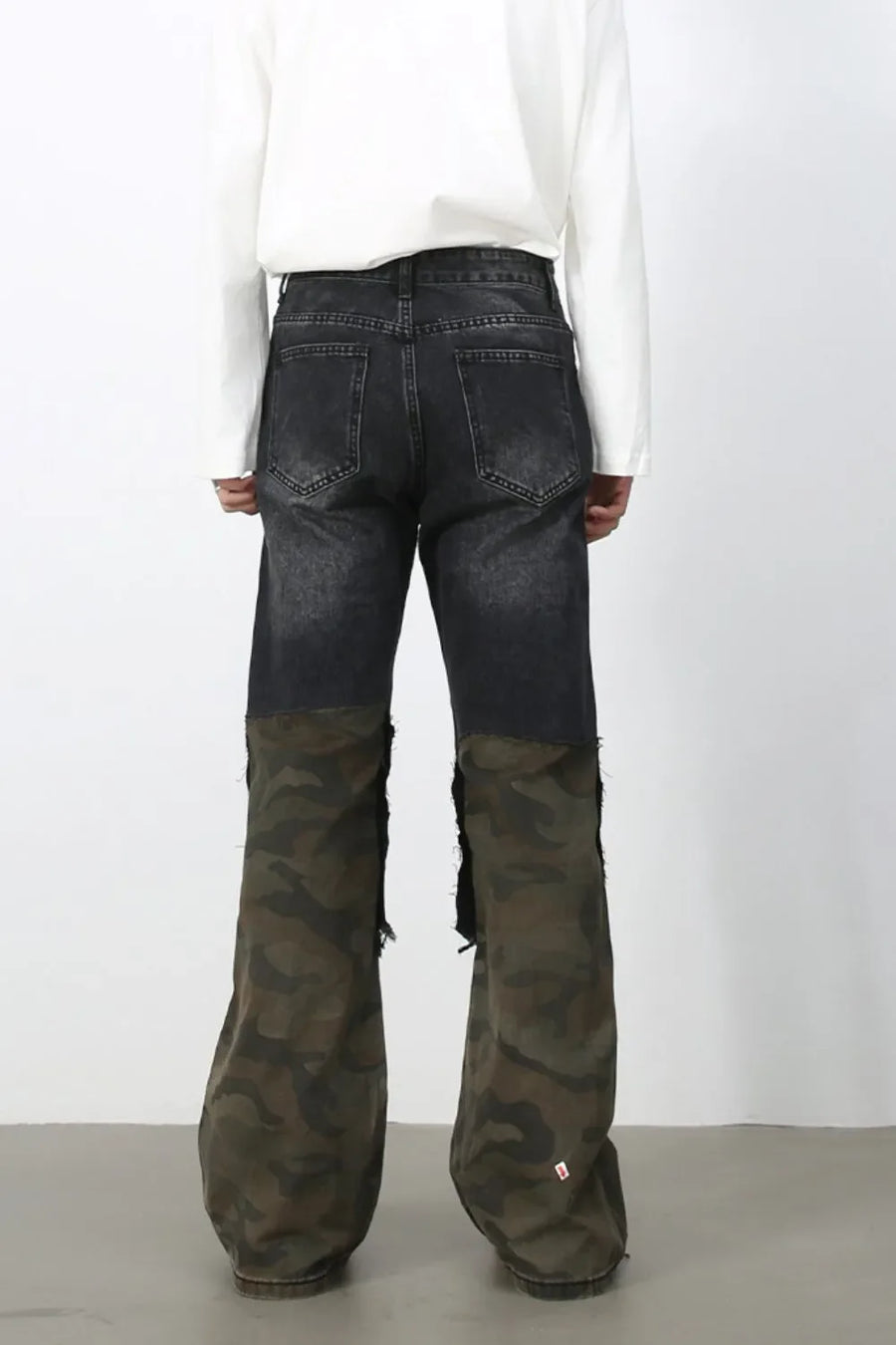 Distressed dark wash flare jeans with camo panel legs and raw hems.