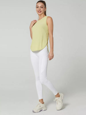Light yellow sleeveless athletic tank top with curved hem, paired with white leggings.