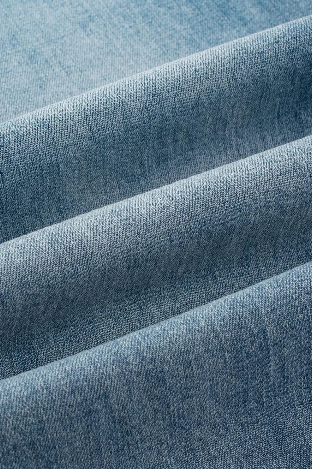 Button-fly wide-leg denim trousers in medium wash, showing fabric texture.