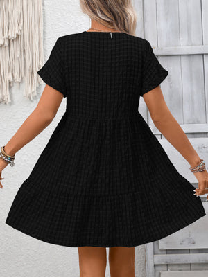 Black plaid V-neck mini dress with short sleeves and tiered skirt.