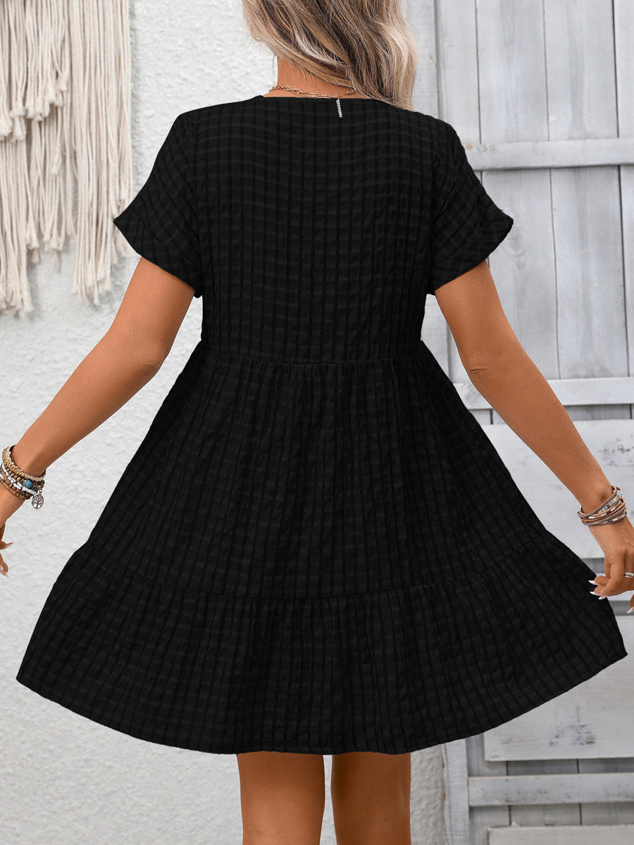 Black plaid V-neck mini dress with short sleeves and tiered skirt.