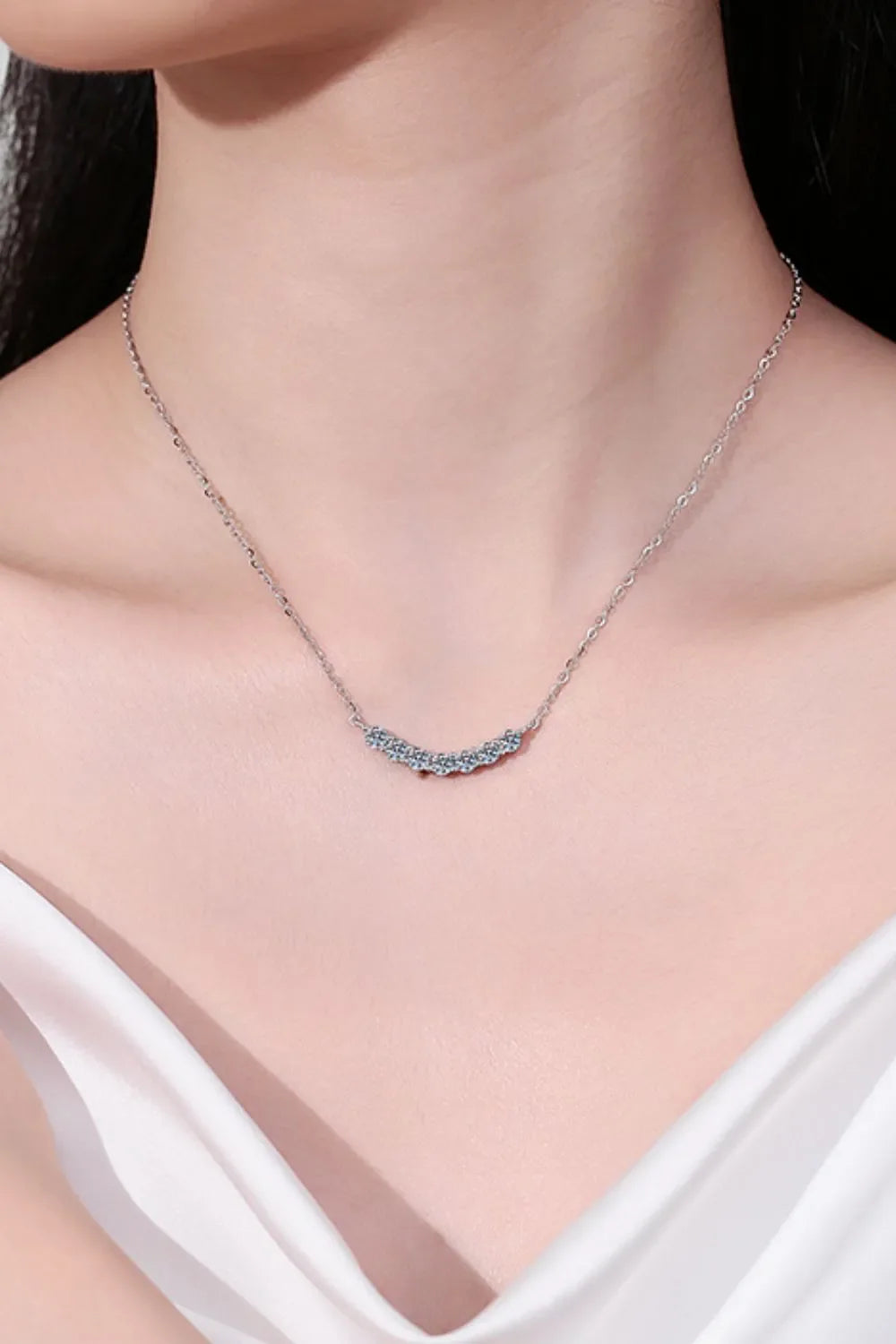 Silver moissanite necklace with a curved row of sparkling stones.