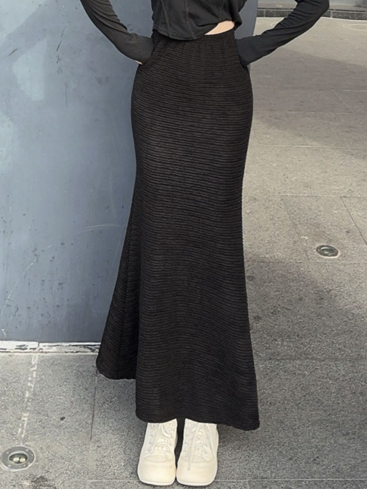 Black textured knit mermaid skirt with a flared hem, styled with a cropped top and white sneakers.