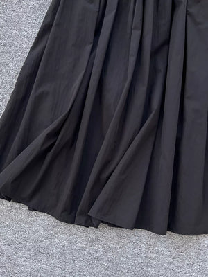 Black a-line skirt with gathered waist and pockets, shown up close.