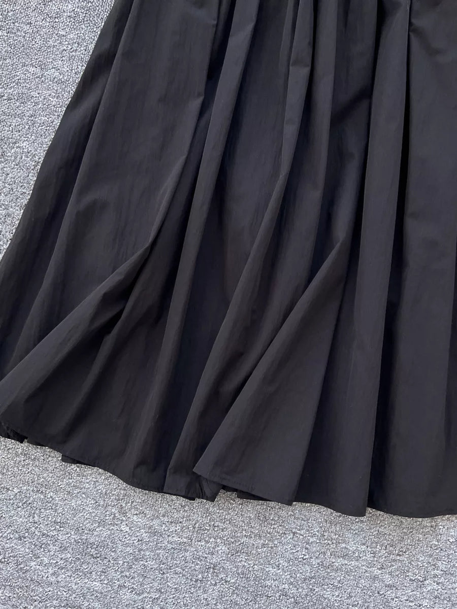 Black a-line skirt with gathered waist and pockets, shown up close.