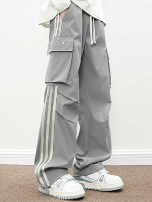 Oversized gray cargo pants with flap pockets and triple stripe detail.