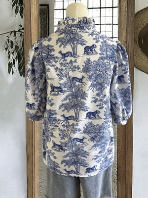Toile de Jouy half sleeve blouse with blue and white pastoral scene pattern and ruffled collar.