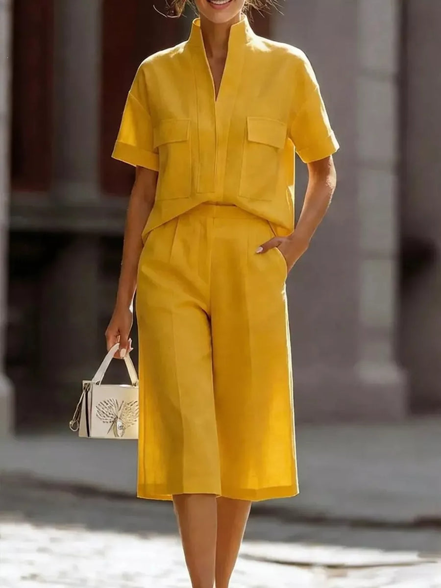 Yellow two-piece set with short sleeves, collar, and pocketed top, paired with wide-leg cropped pants.