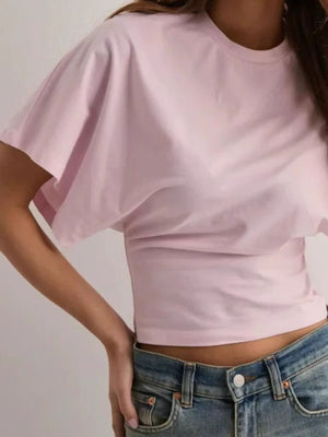 Blush pink batwing sleeve t-shirt with a fitted waist, styled with jeans.