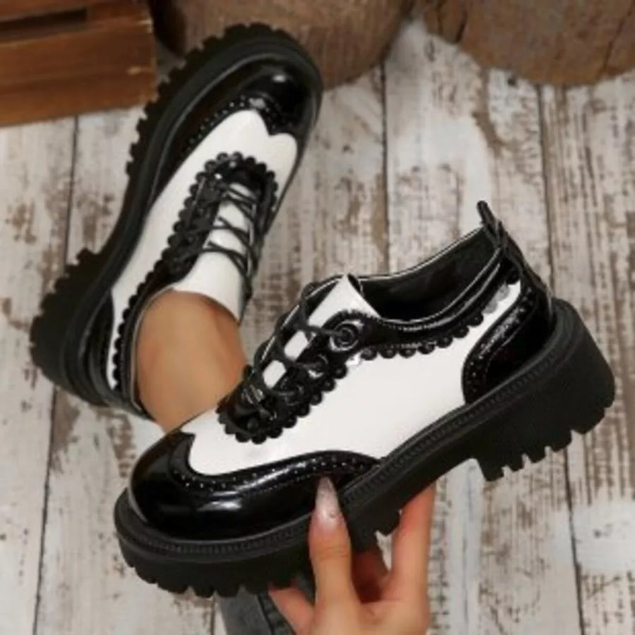 Round toe platform loafers with brogue detailing in black and white patent leather.